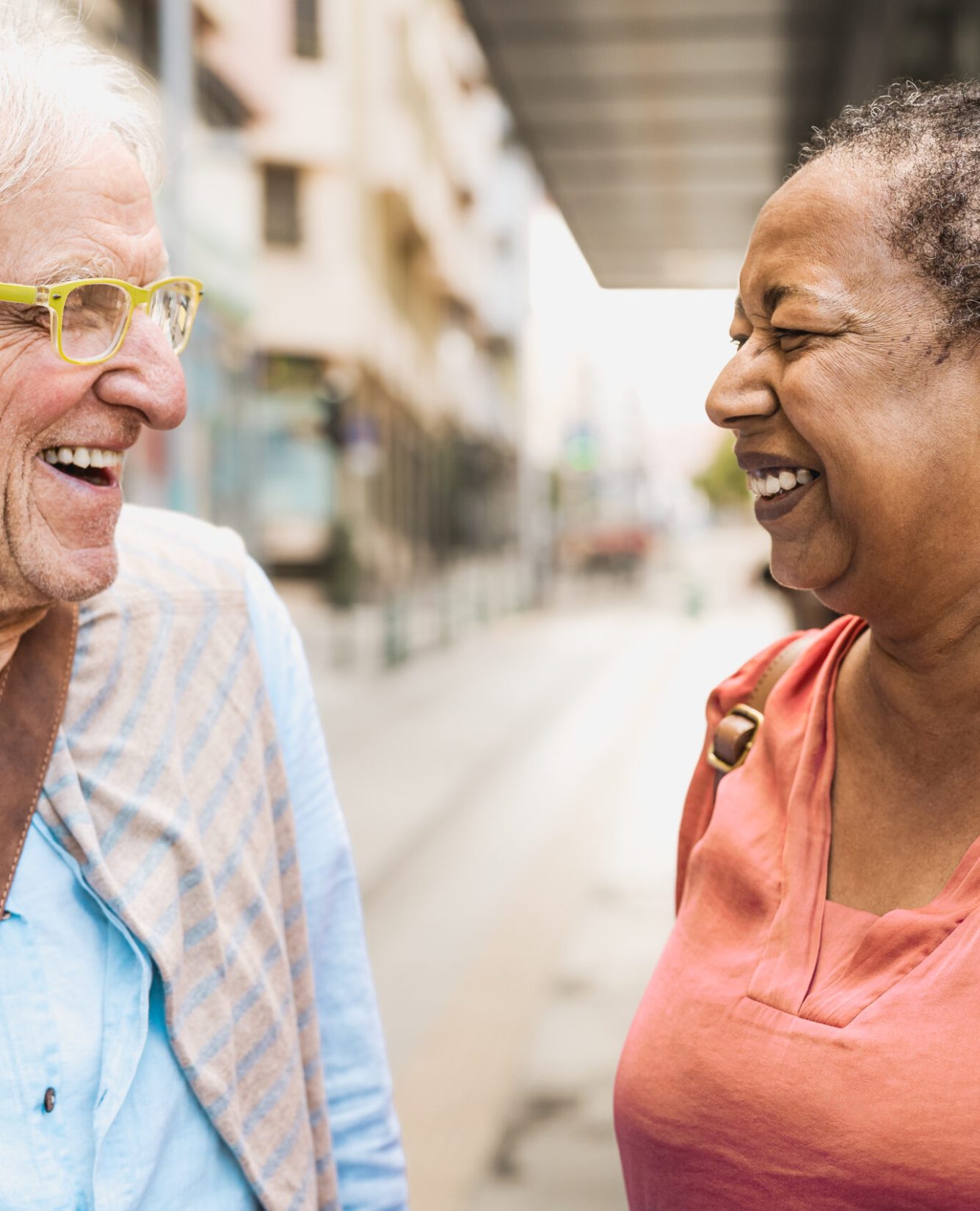 Happy multiracial senior friends talking while waiting at the bus station